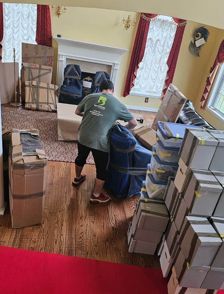 Moving company worker packing boxes in a living room for a US move.