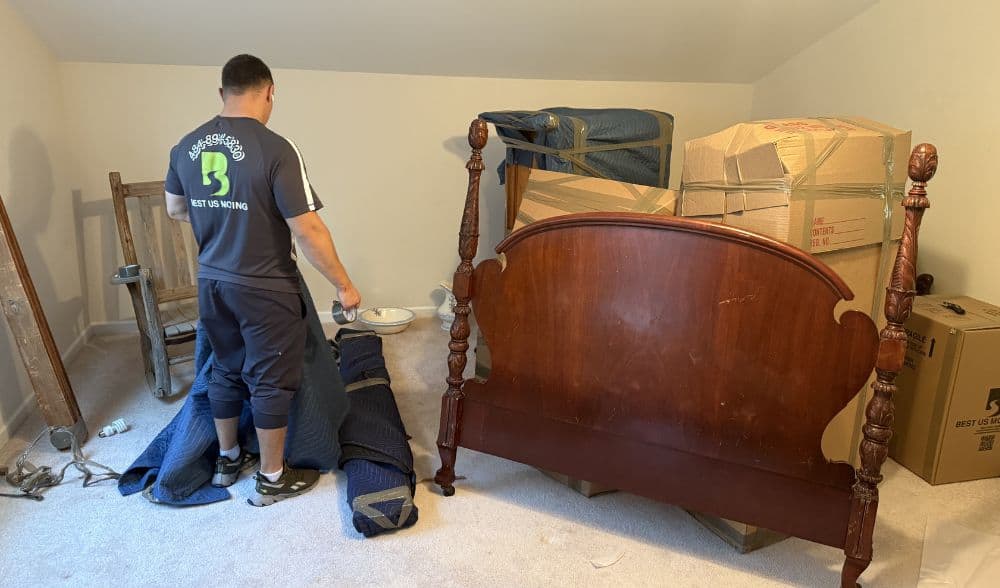 Efficient moving process with professional movers packing belongings in a bedroom.