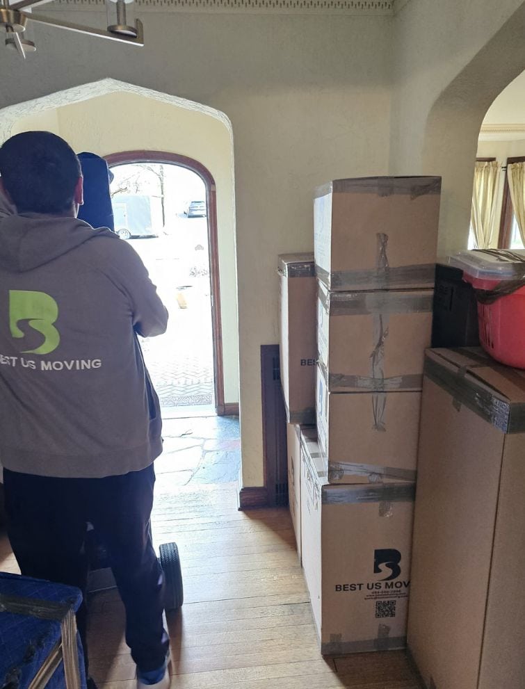 Moving company employee with boxes at home, ready for relocation services.