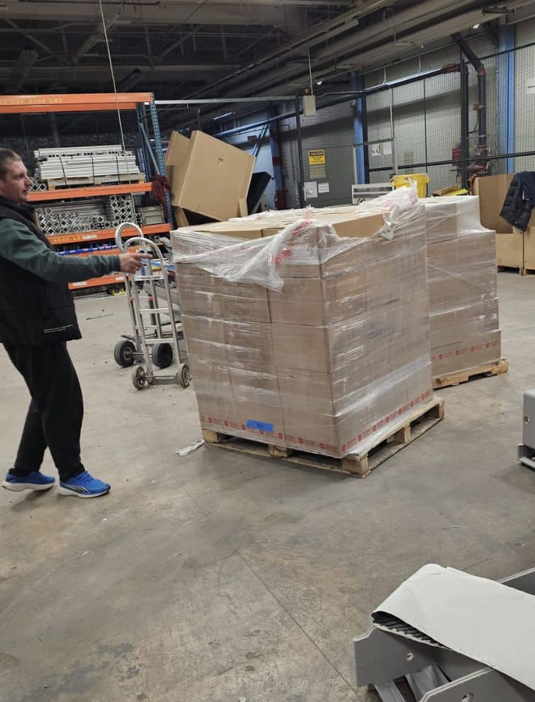 Moving pallets with boxes at a warehouse for US relocation services.