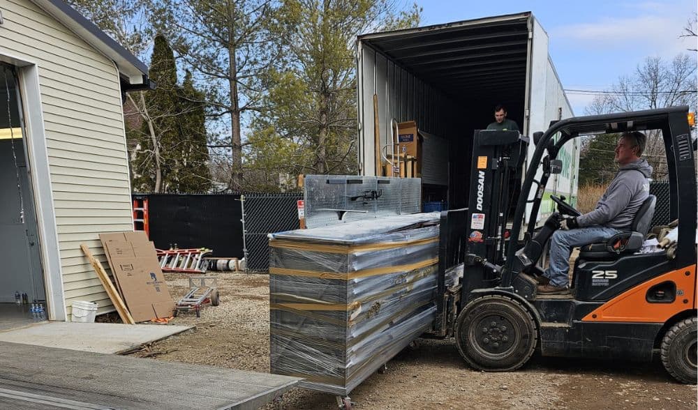 Efficient moving process with forklift and packed furniture outdoors in a residential area.