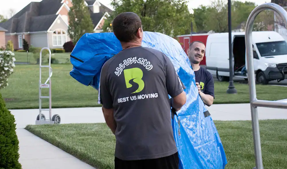 Professional movers from Best US Moving handling large items outdoors in a residential area.
